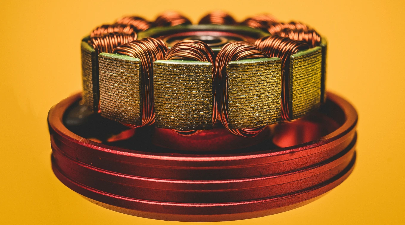 Photo by Mika Baumeister from Unsplash: macro photography of a drone motor with an orange background